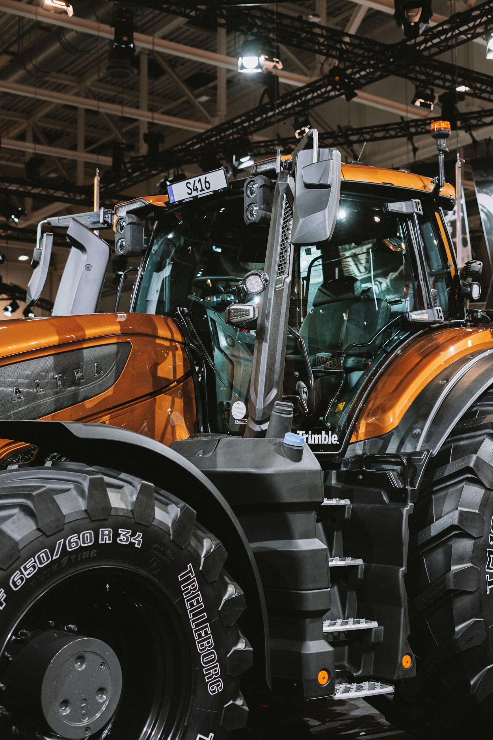 Close-up of a modern orange tractor with advanced features on display indoors.