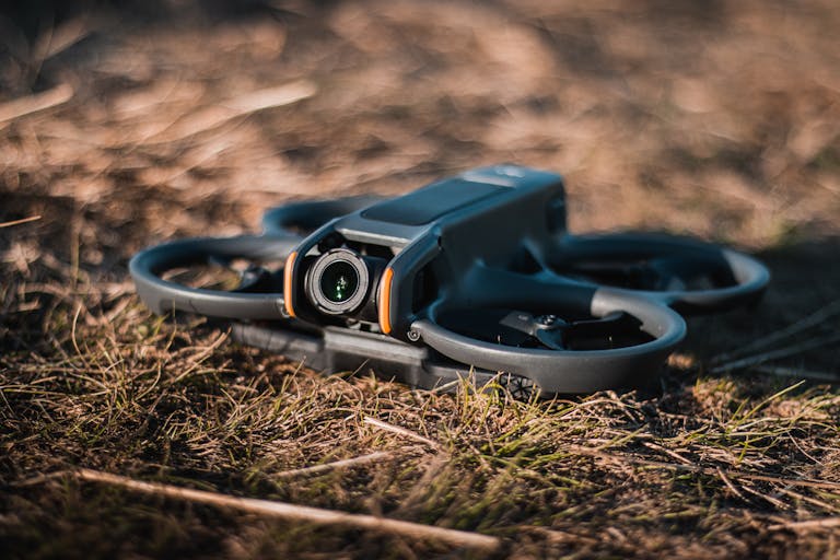 Detailed close-up of a drone resting on grassy terrain under daylight, showcasing modern technology.