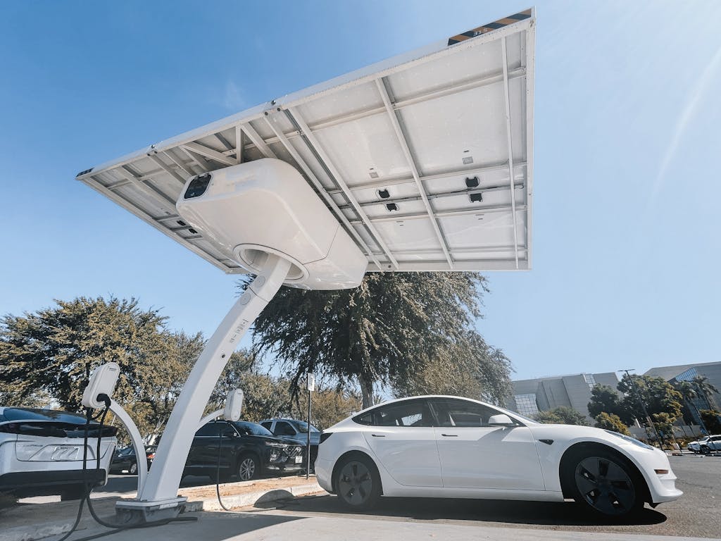 Electric car charging under a modern solar panel station, showcasing clean energy technology.