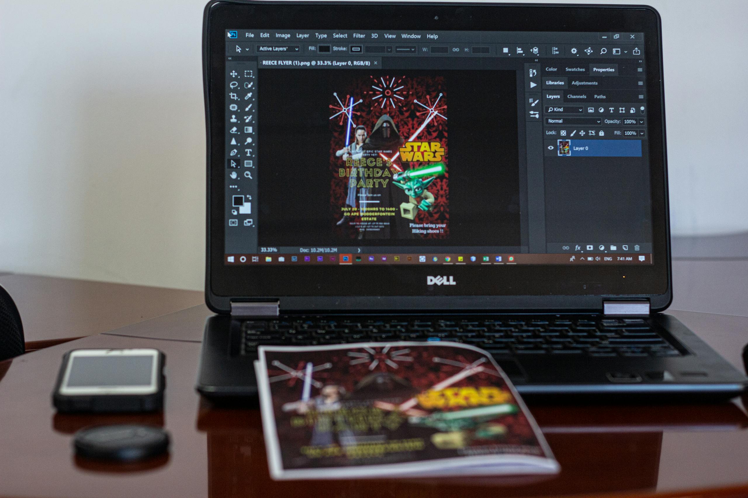 A laptop displaying Star Wars party invitation design in a workspace setting.