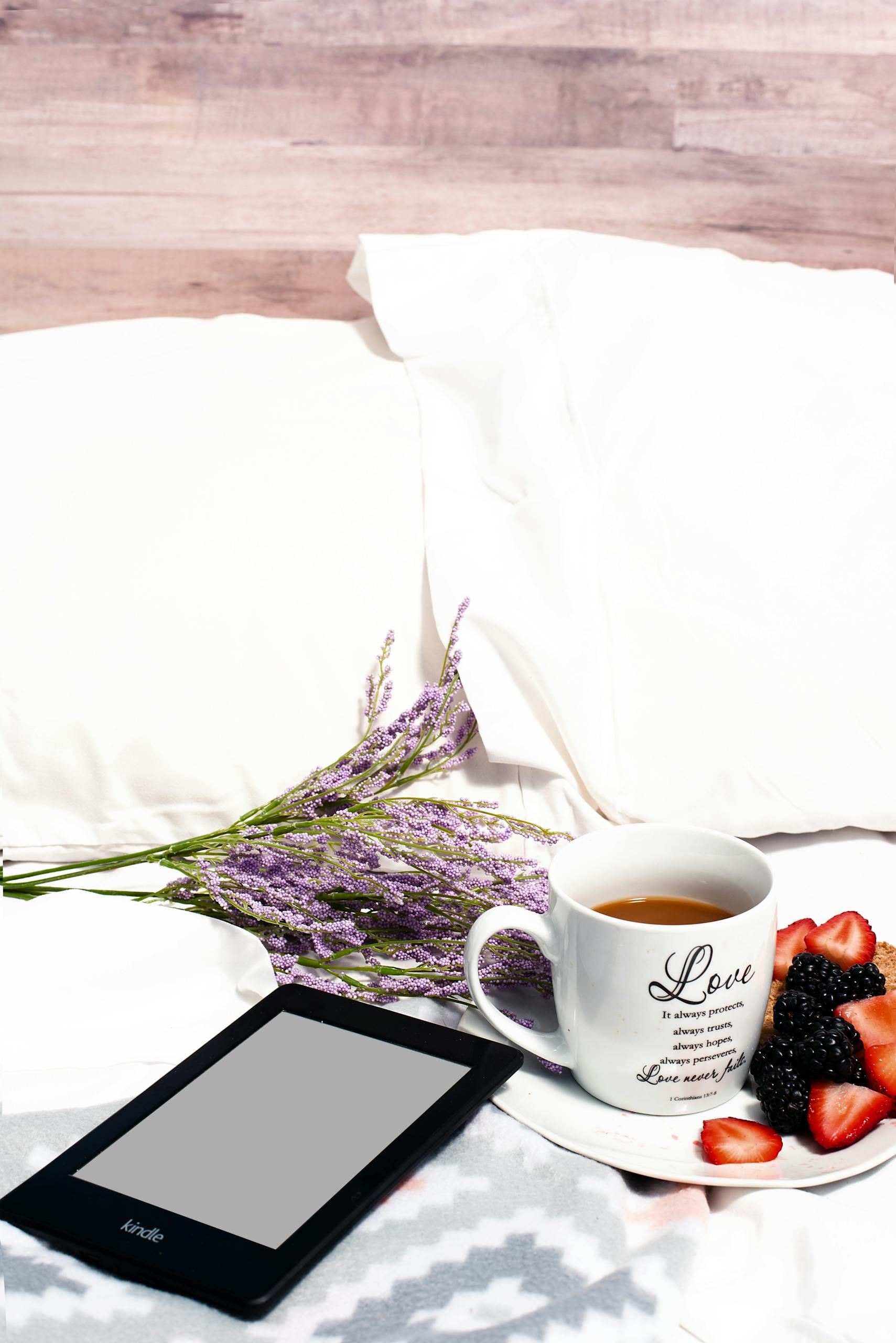 Relaxing breakfast in bed with tea, fruit, lavender, and a tablet for a peaceful morning.