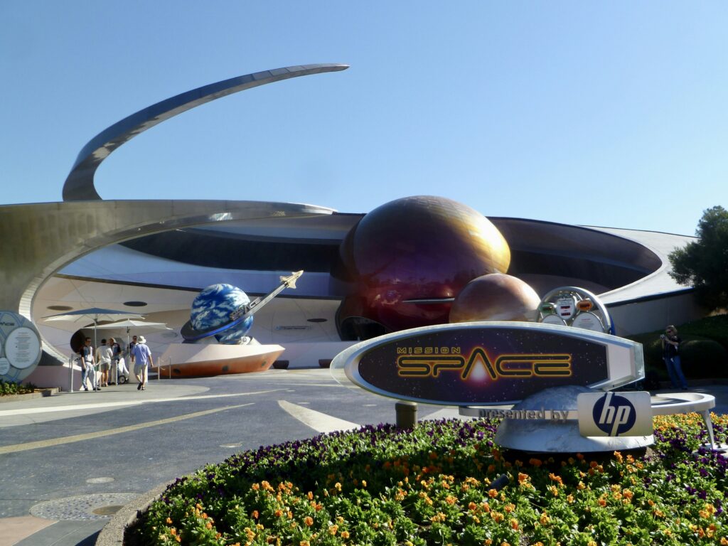 Exterior view of Mission: SPACE at Epcot, capturing the spirit of space exploration news with themed sculptures and a sign.